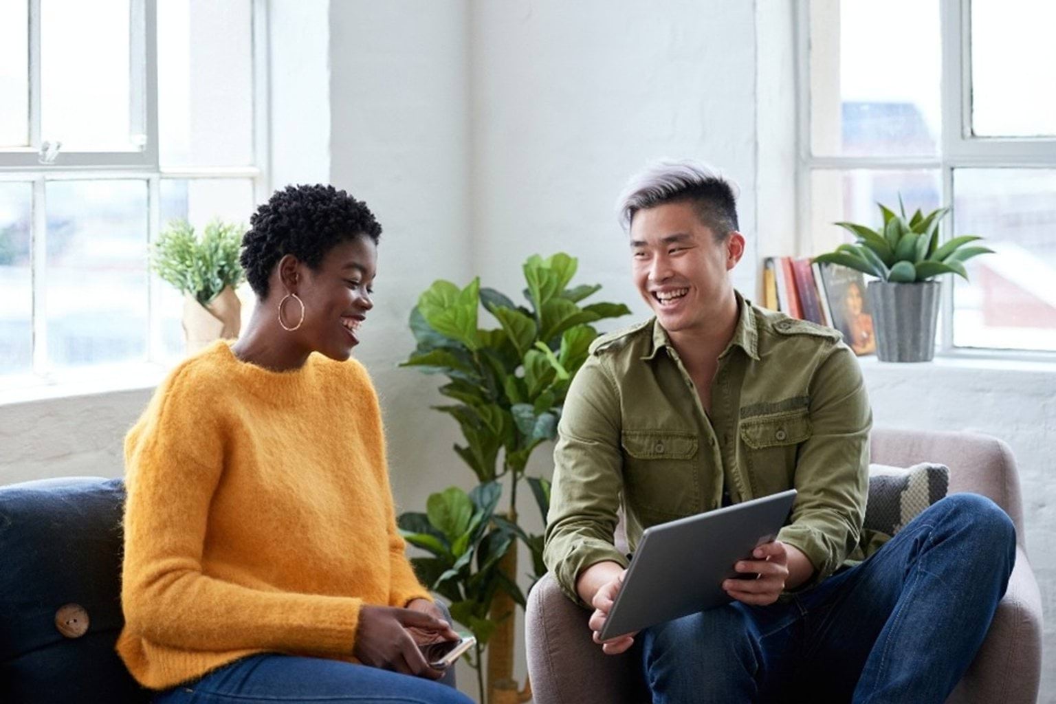 Two smiling people looking at tablet.