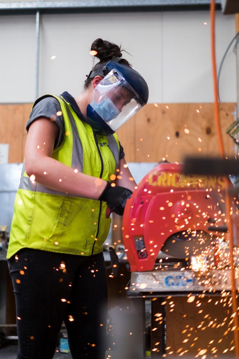 A female apprentice in full PPE operating a machine