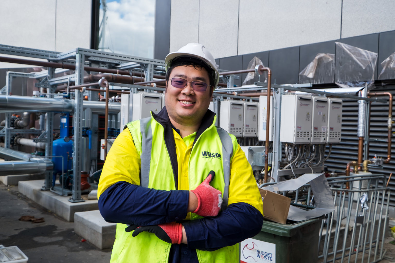 Portrait of a male worker wearing a hi vis vest and a hard hat smiling in a factory