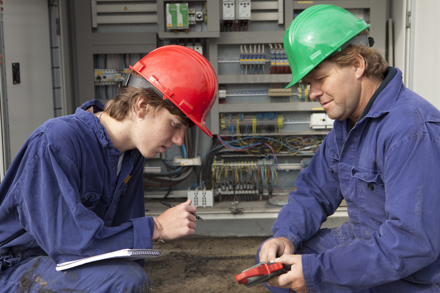 A female electrician learning from an instructor at work