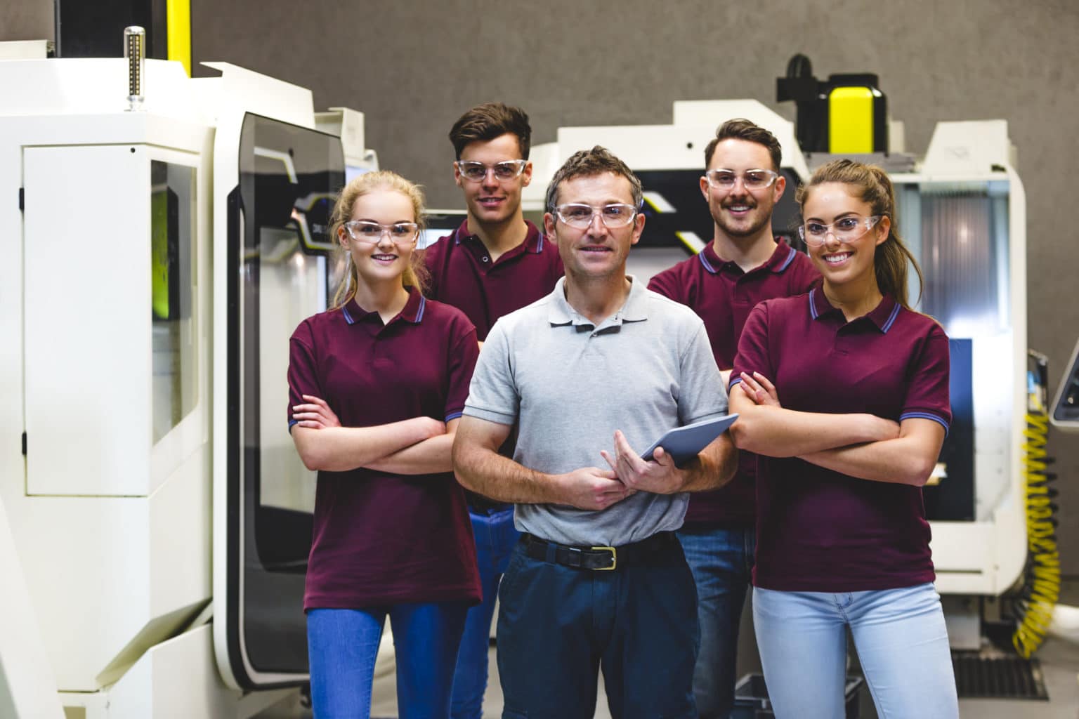 A group of manufacturing apprentices and their trainer smiling